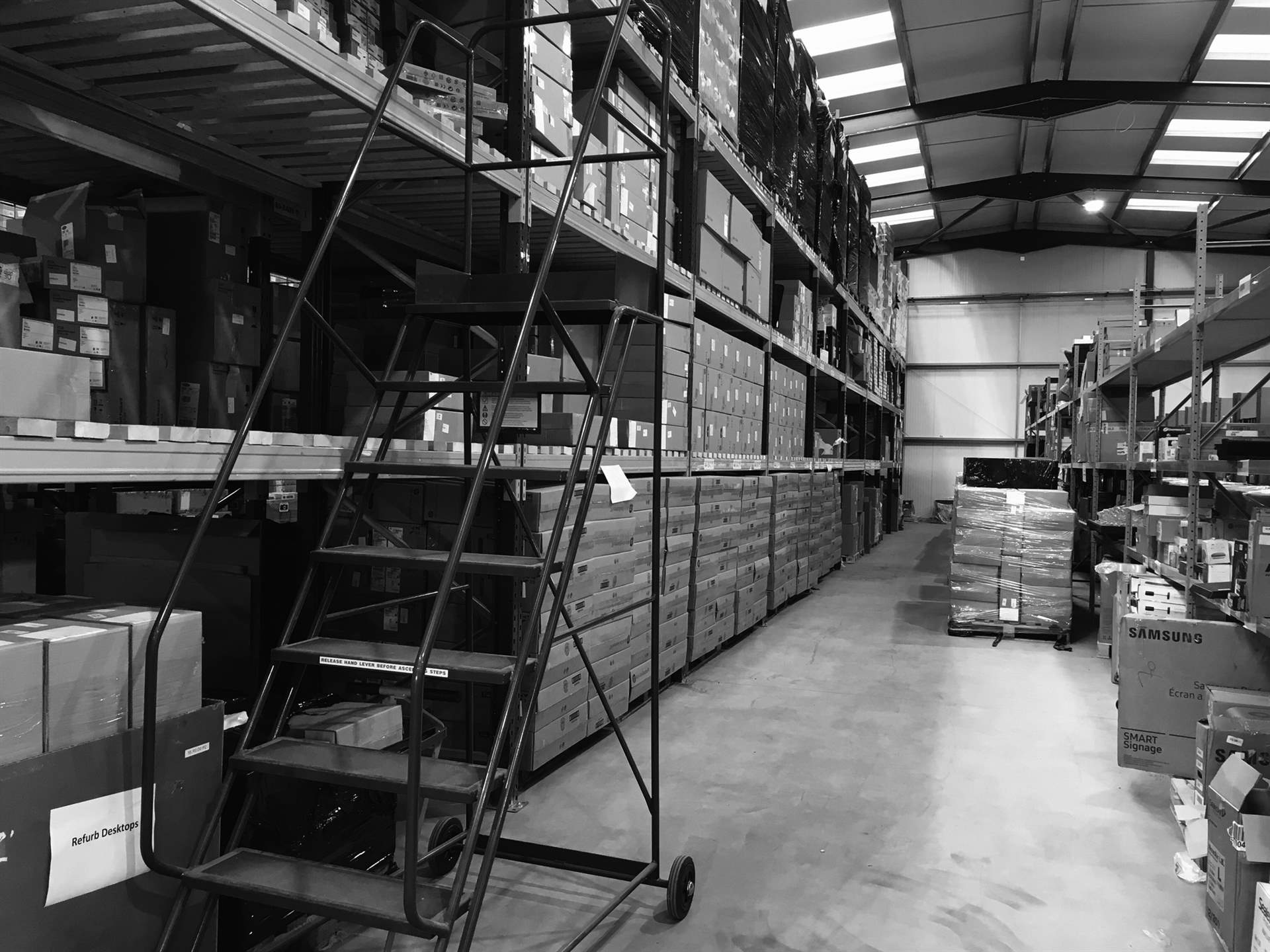 Warehouse racking stacked with boxed equipment, pallets and packaging awaiting sorting and routing
